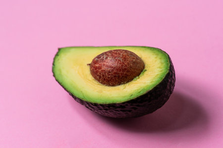 Half of a fresh avocado on a pastel pink background. Closeupの写真素材