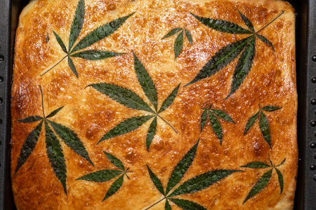 Baked homemade corn bread with cannabis butter, decorated with fresh marijuana leaves. Full frameの写真素材