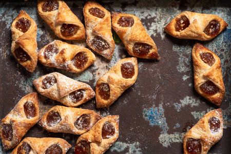 A top-down view of homemade baked pastries filled with fruit filling, showcasing their beautiful...