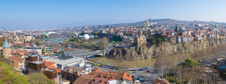 Stunning panoramic view captures the vibrant cityscape of Tbilisi, Georgia, under a bright, clear...
