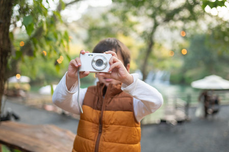 A delightful moment as a young boy joyfully points his camera towards the viewer, encapsulating the...