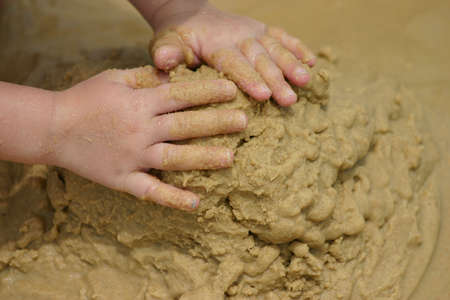 Young childs' hands playing in the sand at the beach