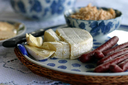 camembert cheese, spicy sausage sticks and crab dip on party platterの写真素材