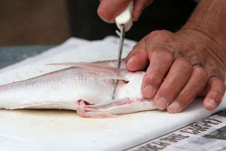 Close up of man filleting fresh fish with knifeの写真素材
