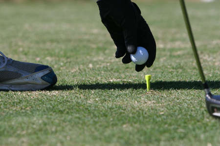 golfer placing golf ball on tee - getting ready to tee-offの写真素材