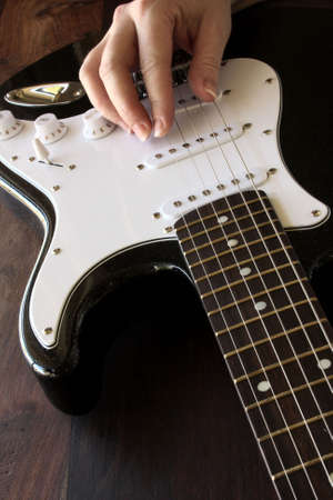 close up of black and white electric guitar with musicians handの写真素材