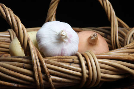 onion garlic and potatoe in wicker basketの写真素材