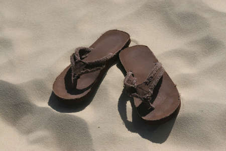 pair of brown thongs / sandals in sand on beachの写真素材