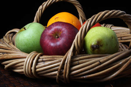 wicker basket with fresh fruit - apples orange pearの写真素材