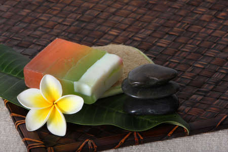 Tropical white yellow frangiapani / plumeria flower on bamboo woven matt with natural soap and loofahの写真素材