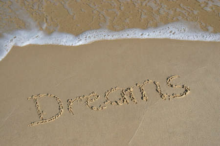 dreams written in sand on beach with waves in background - vacationの写真素材