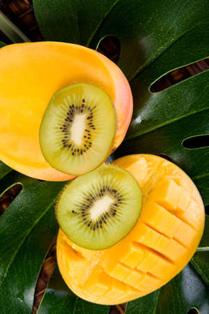 fresh sliced tropical mango on green leaves with kiwi fruitの写真素材