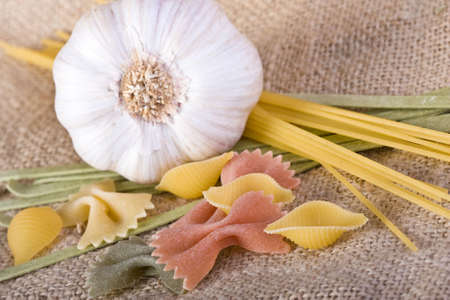 fresh garlic cloves and raw pasta on hessian backgroundの写真素材