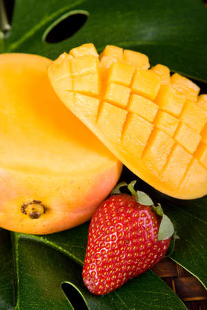 fresh sliced tropical mango on green leaves with strawberryの写真素材