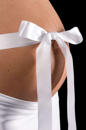 Close up of pregnant mother-to-be tummy with satin ribbonの写真素材