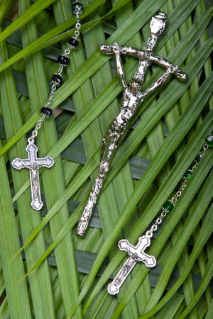 close up of rosaries and crucifx on palm leavesの写真素材