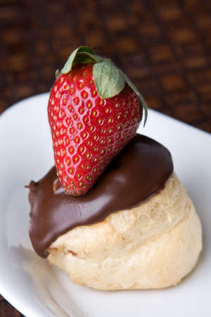close up of chocolate profiterol and strawberry dessert in white dish