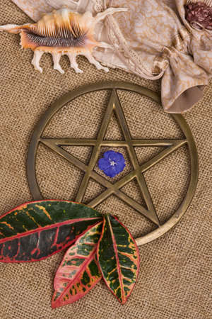 close up of brass pentagram / pentacle on burlap - hessian background