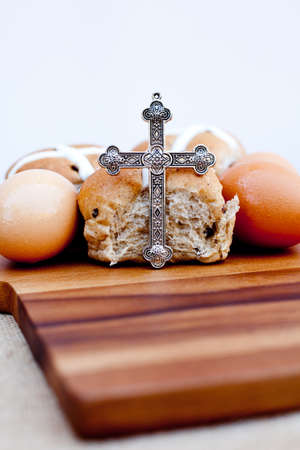 Easter - crucifix, hot cross buns and eggs on wooden cutting boardの写真素材