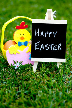 Easter egg hunt egg felt basket with Chick decoration on grass background with blackboard