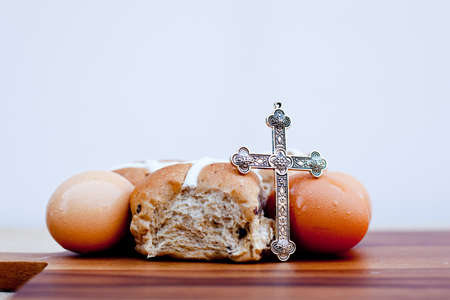 Easter - crucifix, hot cross buns and eggs on wooden cutting boardの写真素材