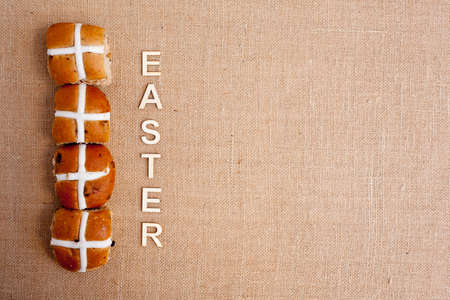 Easter - Hot cross buns with Easter in wooden letters on burlap backgroundの写真素材