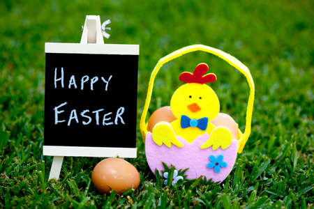 Easter egg hunt egg felt basket with Chick decoration on grass background with blackboard