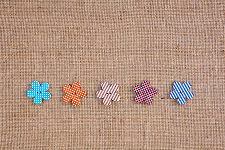 background - natural color burlap hessian with flower buttonsの写真素材