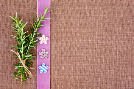 background - brown color burlap hessian with pink ribbon border and sprig of rosemaryの写真素材