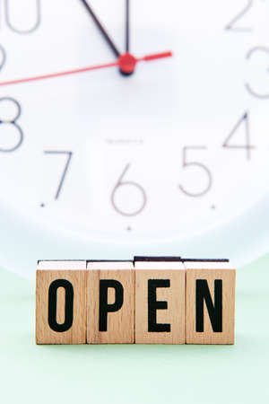 Open time - wooden block letters with out of focus clock face in backgroundの写真素材