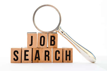 Job Search - wooden block letters and magnifying glass with white backgroundの写真素材
