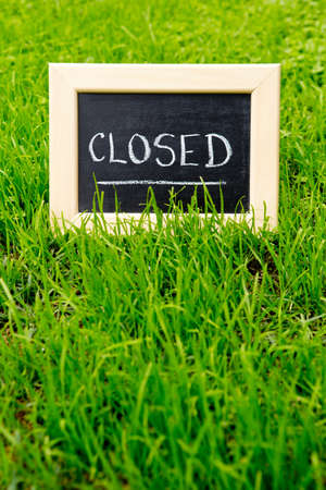 Closed Sign handwritten in chalk on blackboard with green grass backgroundの写真素材