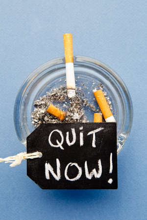 Stop Smoking - Quit Now - with cigarettes, ashtray and blackboard on blue backgroundの写真素材