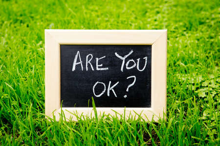 Are You OK - handwritten in chalk on blackboard with green grass backgroundの写真素材