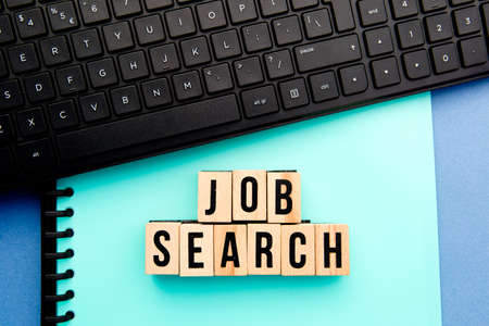Job Search - wooden block letters with notebook and computer keyboard in backgroundの写真素材