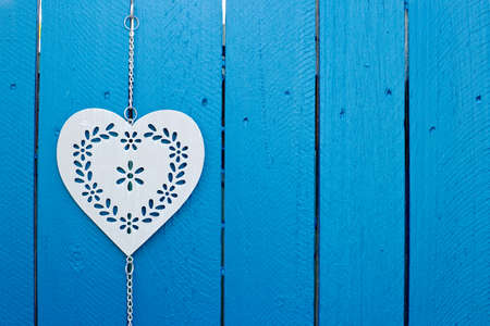 Background - Decorative silver metal heart hanging on blue wooden fence