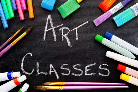 Art Classes handwritten on chalkboard with art equipmentの写真素材