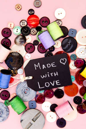Sewing - Made with Love blackboard with buttons and thread on pink backgroundの写真素材