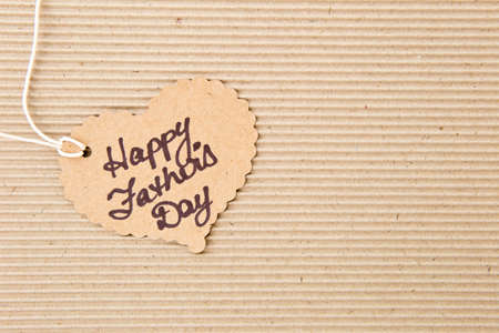 Happy Father's Day - on heart shape tag on corrugated cardboard backgroundの写真素材