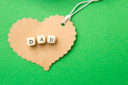 Father's Day - Dad on cardboard heart on green background
