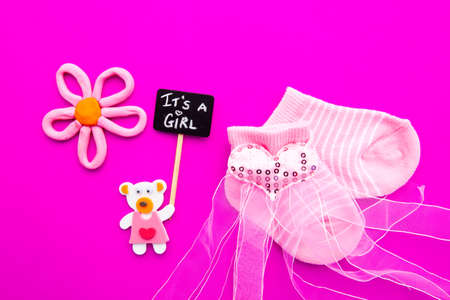 Baby Girl announcement - pink and white socks with bear on pink background with It's a Girl blackboard signの写真素材