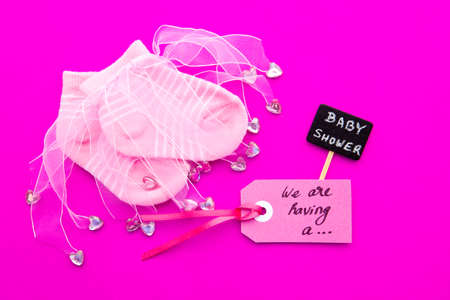 Baby Girl announcement - pink and white socks on pink background with label - we're having a girl and  Baby Shower blackboard signの写真素材