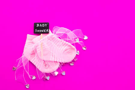 Baby Girl announcement - pink and white socks with ribbon on pink background with Baby Shower on blackboard signの写真素材