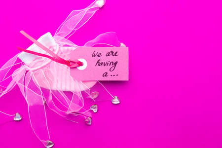 Baby Girl announcement - pink and white socks on pink background with label - we're having a girlの写真素材
