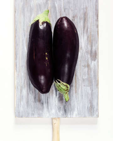 Two black eggplants on a wooden boardの写真素材