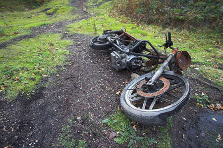 An old rusty motorbike carcass abandoned to decay on a lonely patch of waste ground.