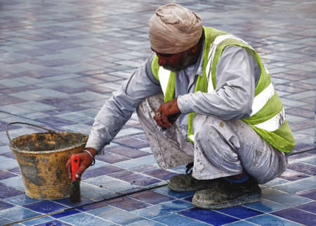 DUBAI, UAE - FEBRUARY 12: Construction worker in Dubai, the original people behind the beuatifican of Dubai. A general image of a worker busy fixing a floor in a contruction site in Dubai on 12th feb 2012. のeditorial素材