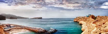 A beautiful building on the sea shore of Muscat with rocky mountain and ocean.の写真素材