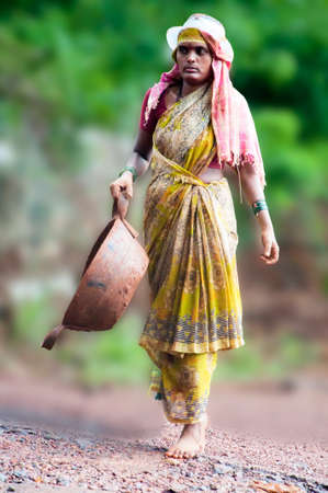 Managlore, India - June 12: A unknown Indian female construction worker carrying out her routine duty of carrying materials on head. Most of the rural constructions are done manually.のeditorial素材