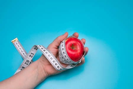 Tomato and measuring tape on the blue background. The concept of diet.の写真素材